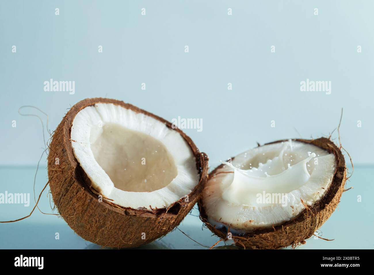 Broken coconut pieces on a blue background. Summer background, free space for decoration. Stock Photo