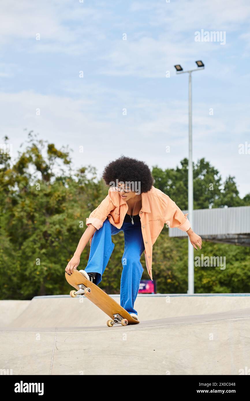 A young African American woman with curly hair performing an impressive trick on her skateboard at a skate park. Stock Photo