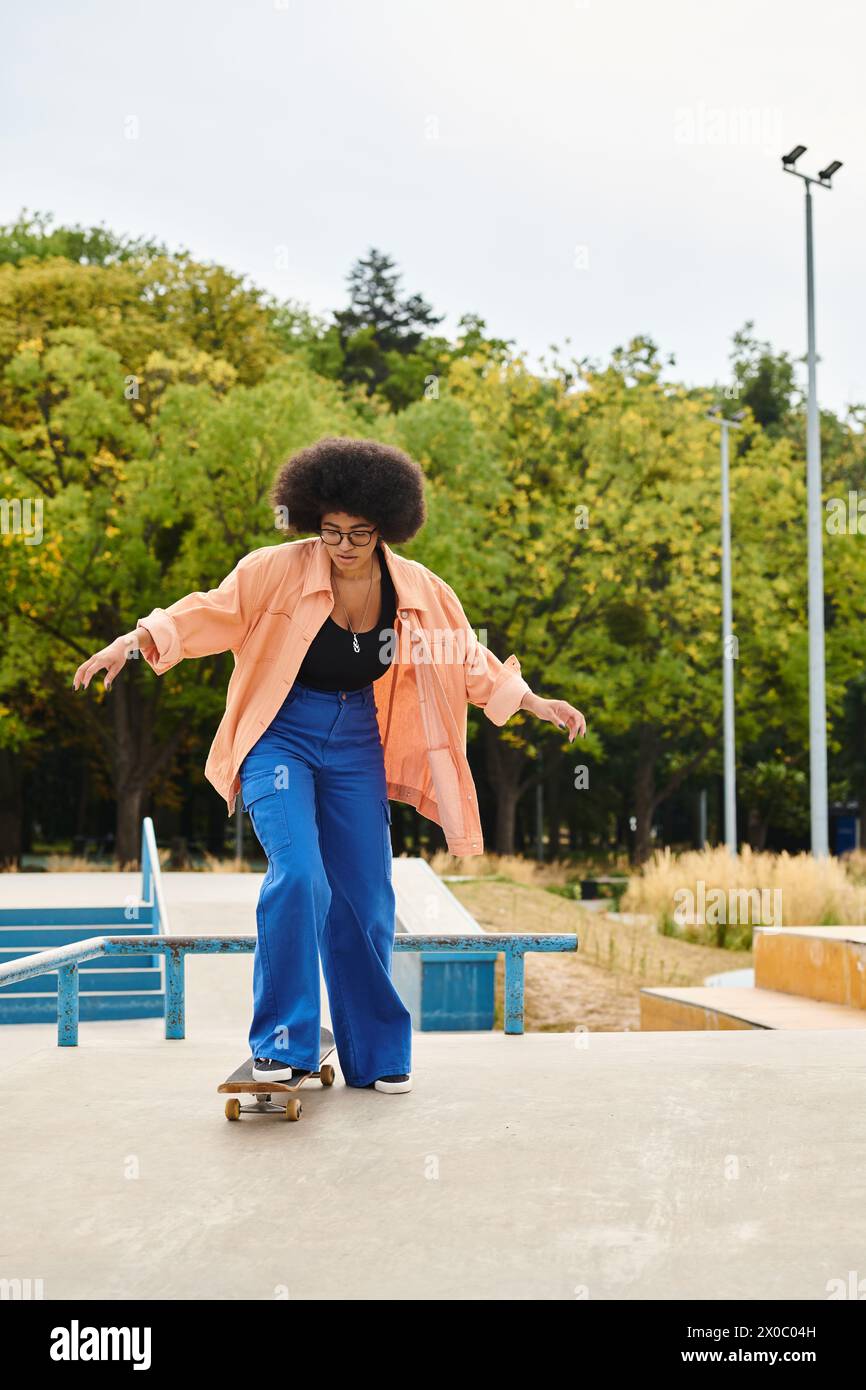 African American woman with curly hair confidently skateboarding on top of a cement slab at a skate park. Stock Photo