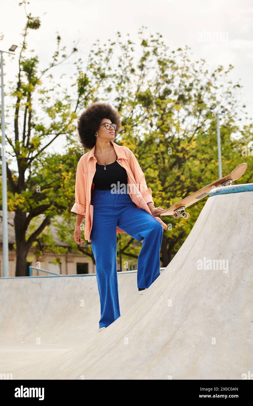 Young African American woman with curly hair confidently skateboarding at a vibrant skate park. Stock Photo