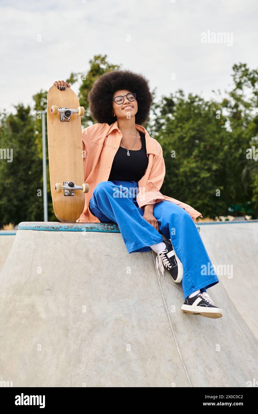 A young African American woman with curly hair sits atop a skateboard ramp. She exudes confidence and determination. Stock Photo