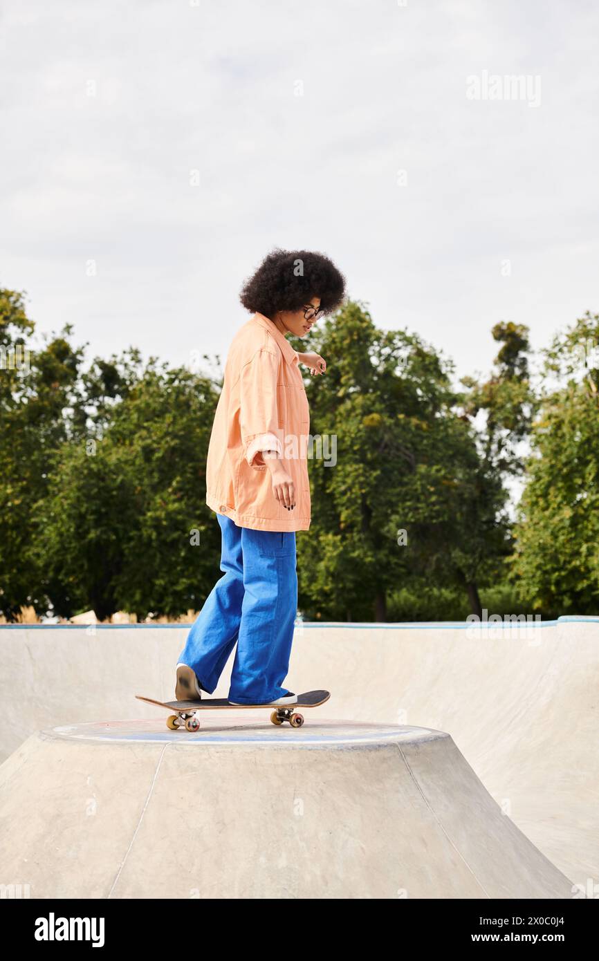 Young African American woman with curly hair showing off her skateboarding skills on a ramp at a skate park. Stock Photo