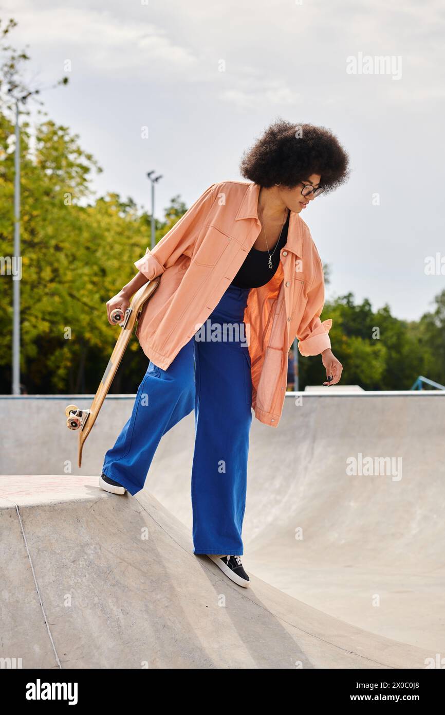 A young African American woman with curly hair confidently skateboarding on a ramp in a vibrant skate park. Stock Photo