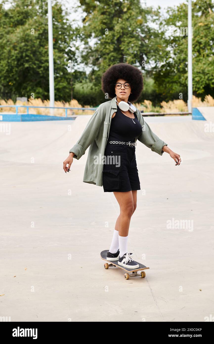 Young African American woman with curly hair skateboarding in a bustling parking lot under the bright sun. Stock Photo
