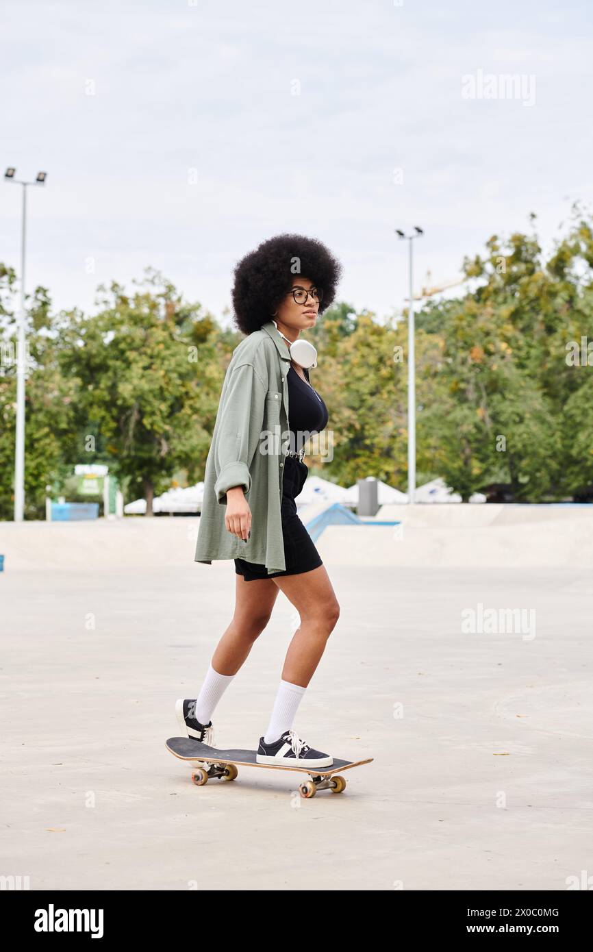 A young African American woman with curly hair effortlessly rides a skateboard in a busy parking lot. Stock Photo