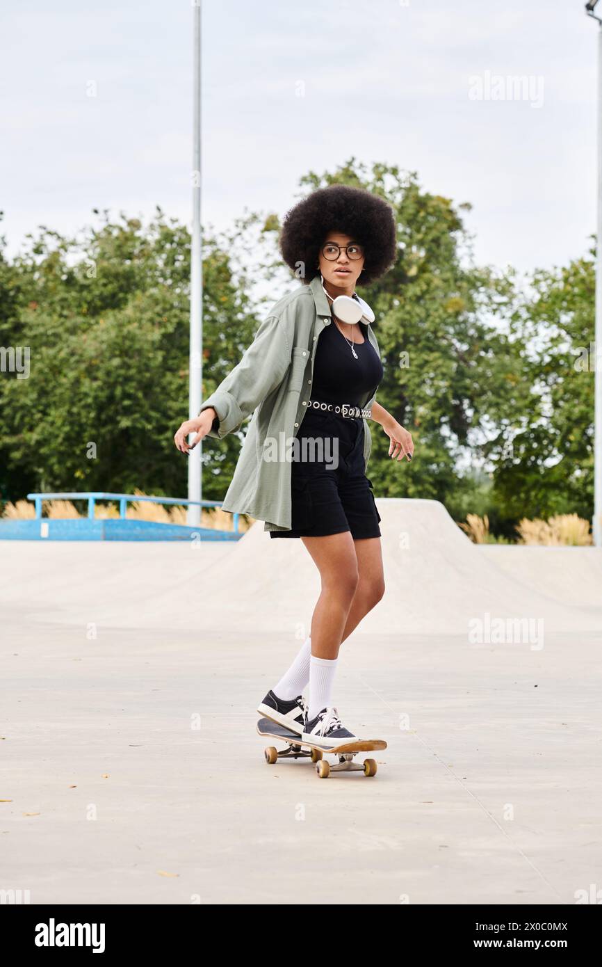 A young African American woman with curly hair confidently rides a skateboard down a bustling urban sidewalk. Stock Photo