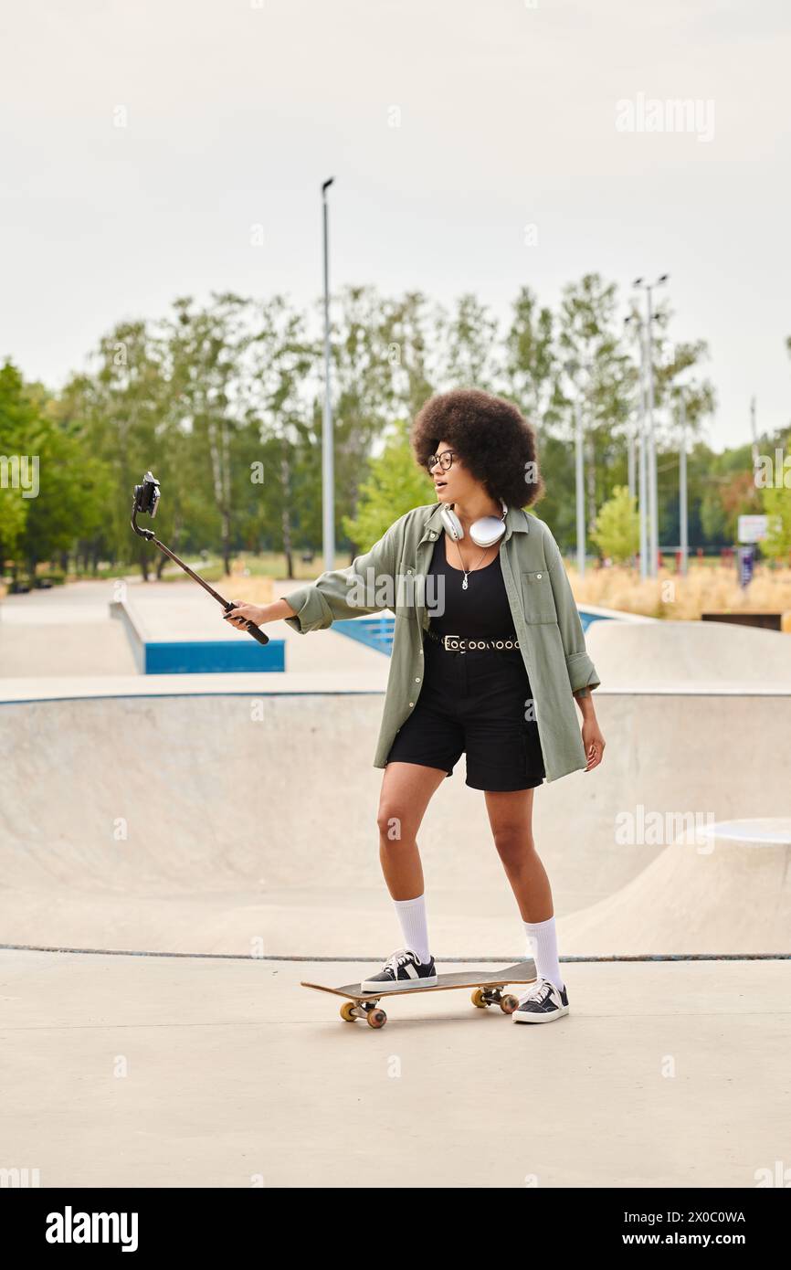 A young African American woman with curly hair confidently rides a skateboard at a bustling skate park. Stock Photo