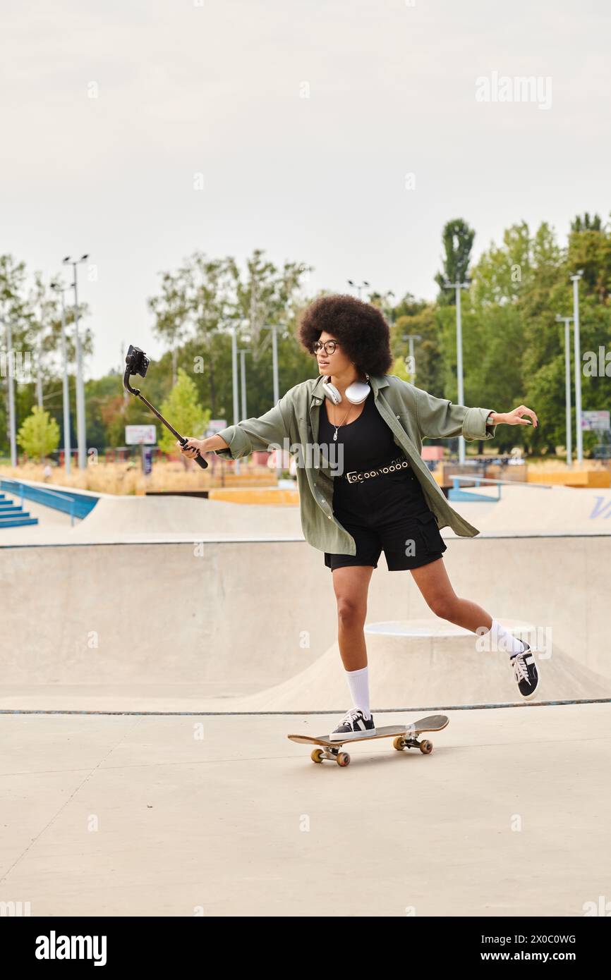 A young African American woman with curly hair confidently rides a skateboard in a vibrant skate park, showcasing her skills. Stock Photo