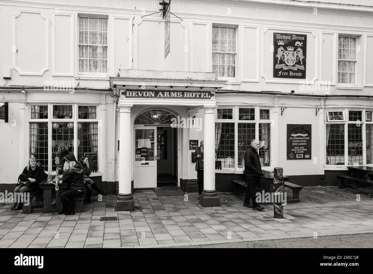 People sitting outside the Devon Arms public house in Teignmouth, Devon, UK. Black & White photography. Stock Photo