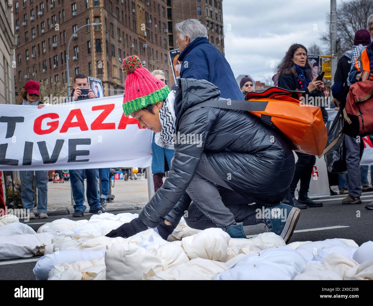 April 6, 2024, Brooklyn, United States: A protester lays down a simulation of a child's dead body during a Pro-Palestine demonstration. Protesters gather at Grand Army Plaza in Brooklyn to protest the killing of children in Gaza. They joined the Jewish Elders & Friends for Ceasefire, a part of Jewish Voice for Peace. The focus was on urging Senator Schumer to cease arming genocide with the tagline ''We demand action, not empty words.'' The route went through the farmerâ€™s market to highlight the famine's impact on Palestinian children. Plans to march to Senator Schumerâ€™s home were thwarted Stock Photo
