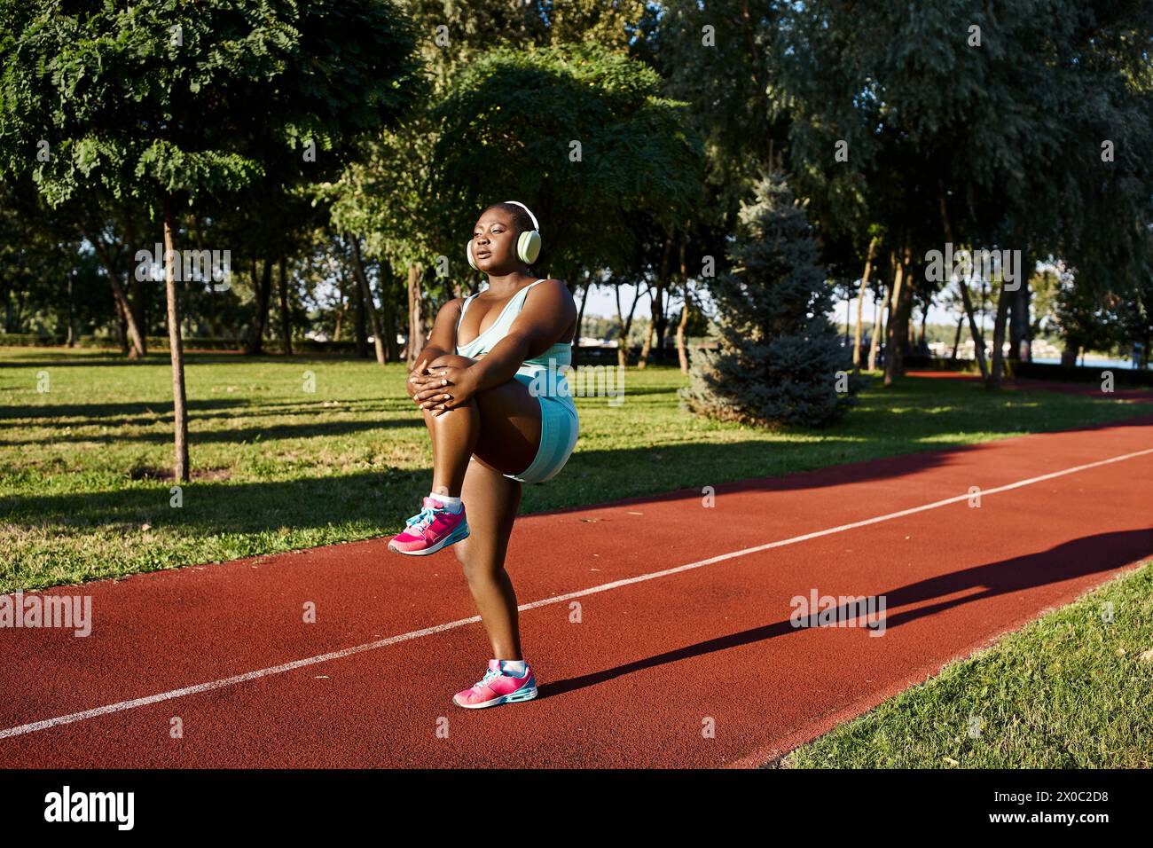 An African American woman in sportswear stands with arms crossed on a track, exuding confidence and strength. Stock Photo