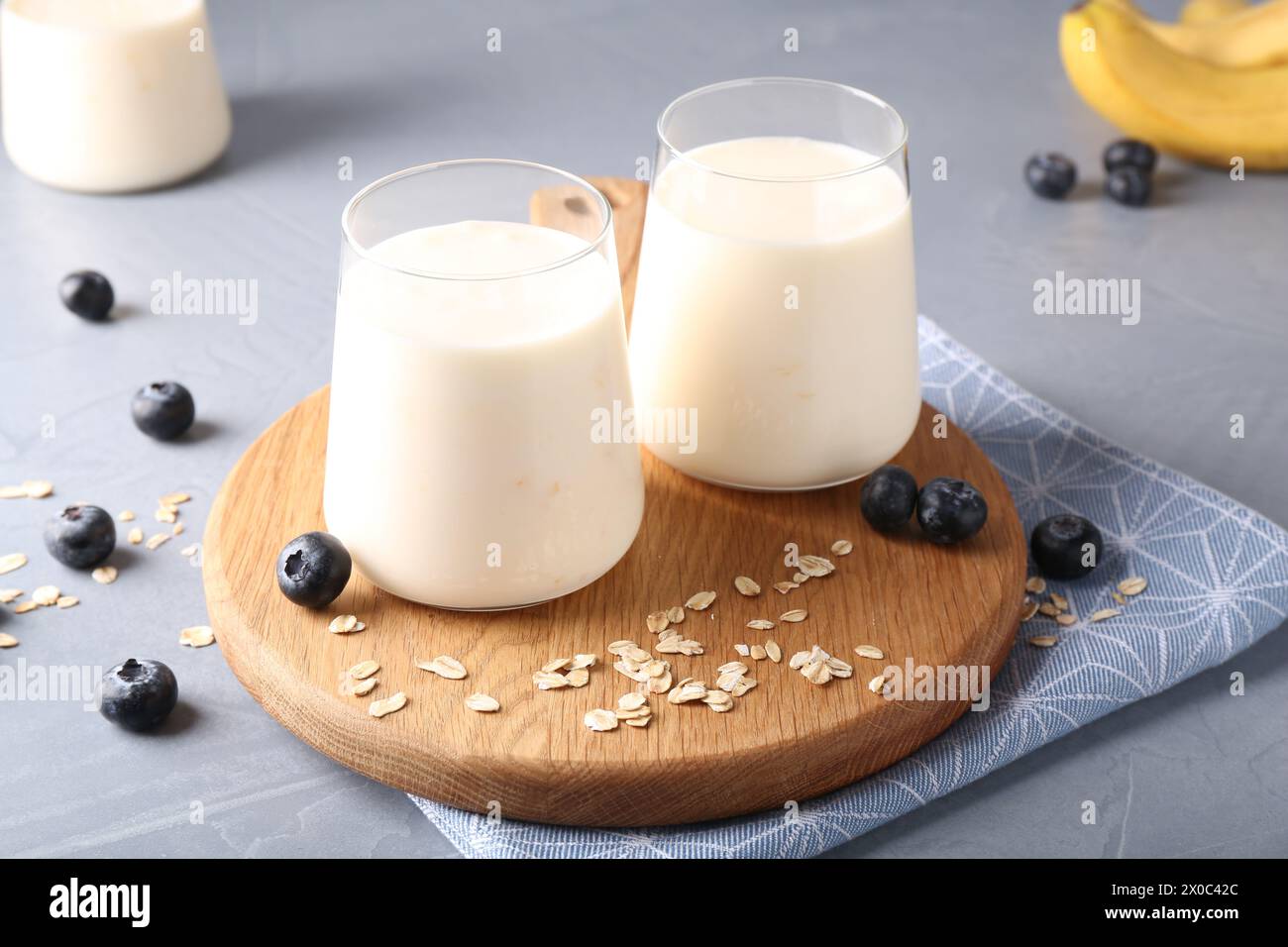 Tasty yogurt in glasses, oats and blueberries on grey table Stock Photo