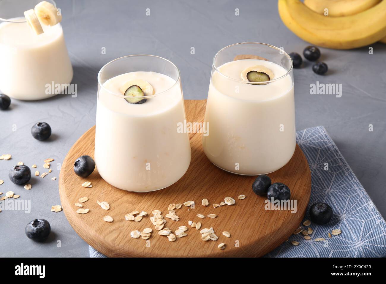 Tasty yogurt in glasses, oats and blueberries on grey table Stock Photo