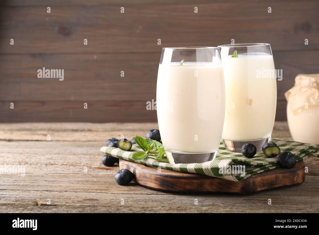 Tasty yogurt in glasses and blueberries on wooden table. Space for text Stock Photo