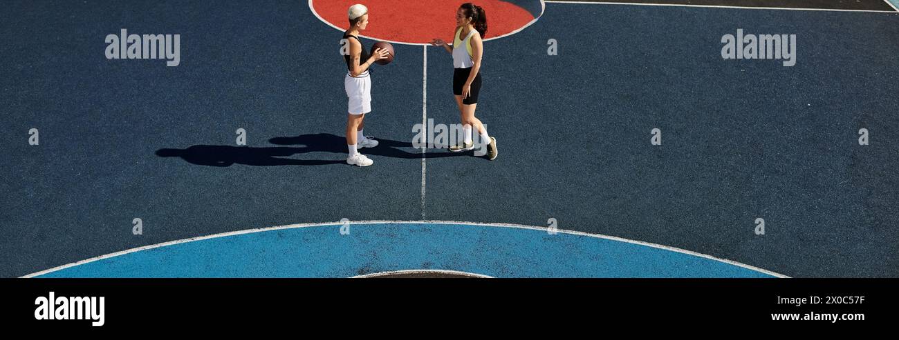 Two athletic women stand confidently on a tennis court, ready to compete under the summer sun. Stock Photo