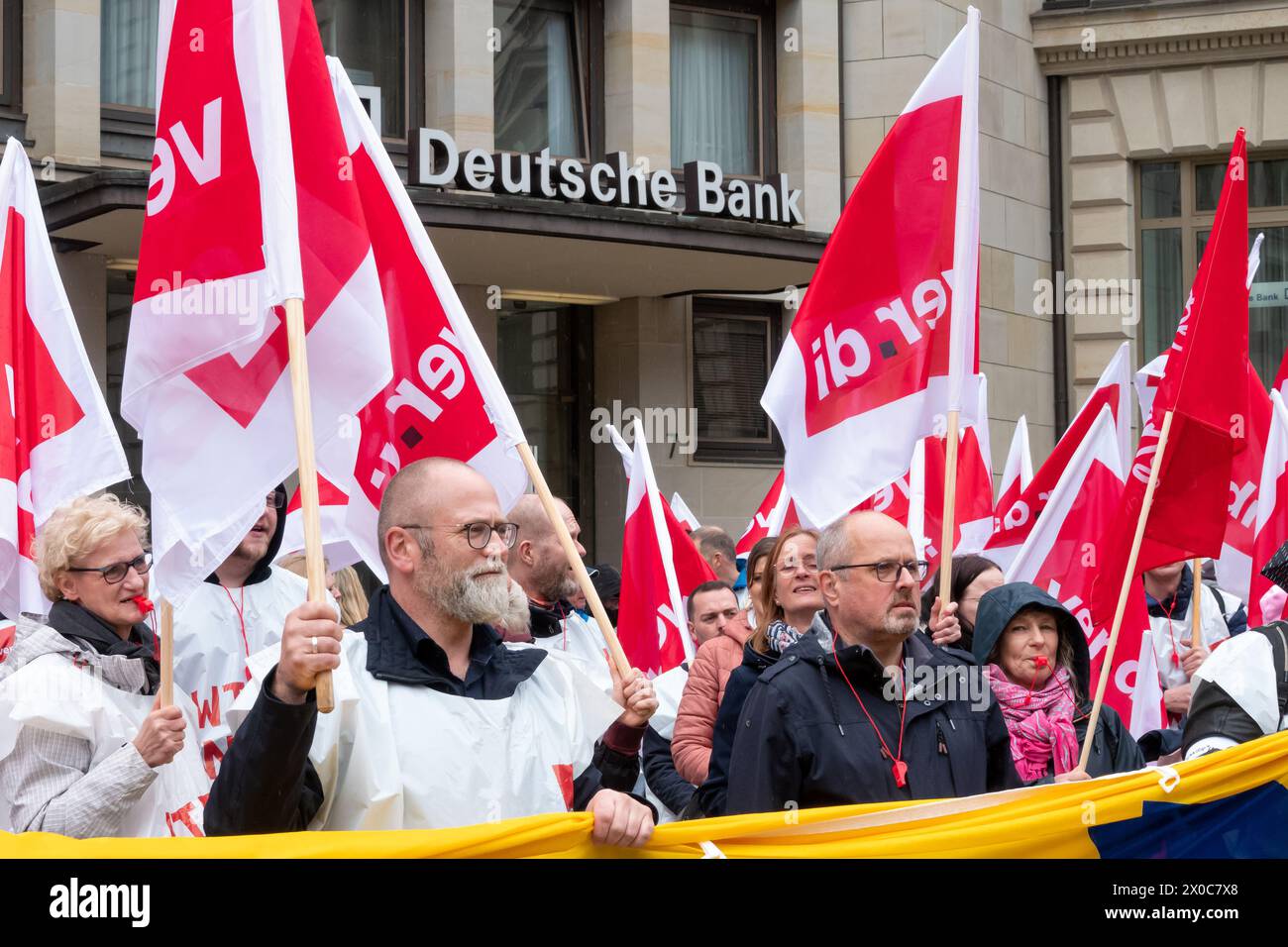 Hamburg, Germany. 11th Apr, 2024. During a warning strike at Postbank, participants in a demonstration stand in front of a Deutsche Bank building during an interim rally. The strike is part of a nationwide wave of strikes by the trade union Verdi to increase the pressure on the employer in the ongoing wage negotiations after the third round of negotiations ended without an agreement. Credit: Bodo Marks/dpa/Alamy Live News Stock Photo