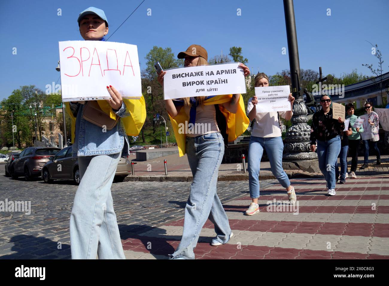 KYIV, UKRAINE - APRIL 11, 2024 - Families of Ukrainian soldiers hold placards as they block the street during a picket to demand clear terms of military service, outside the Valerii Lobanovskyi Dynamo Stadium, Kyiv, capital of Ukraine. Stock Photo