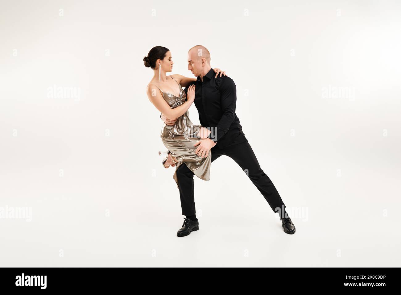 A young man and a woman acrobatically dance together in perfect sync against a white studio backdrop. Stock Photo