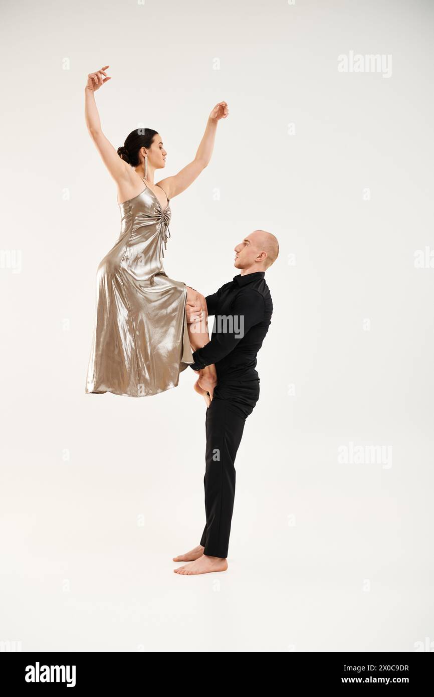 Young man in black and woman in shiny dress perform an acrobatic dance, with the man holding the woman. Stock Photo