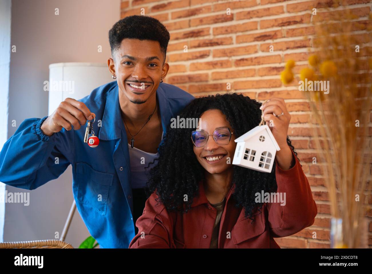 Multiracial couple showing a mini wooden house and a key with a key ...