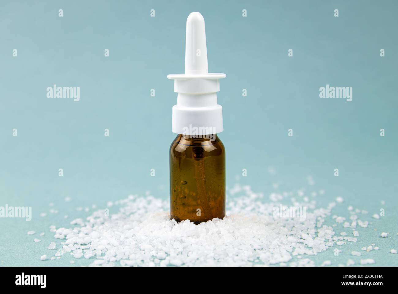 Homemade saline nasal spray bottle on pile of sea salt grains on blue