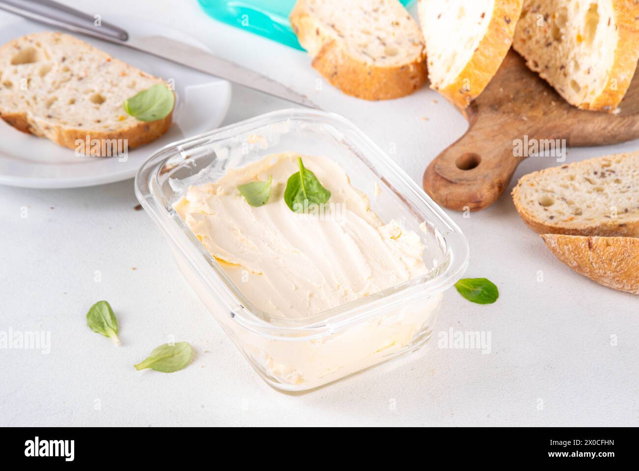 Homemade Vegan Butter, non-dairy creamy, plant based alternative butter with soy bean leave, and home baked bread on kitchen white table background Stock Photo