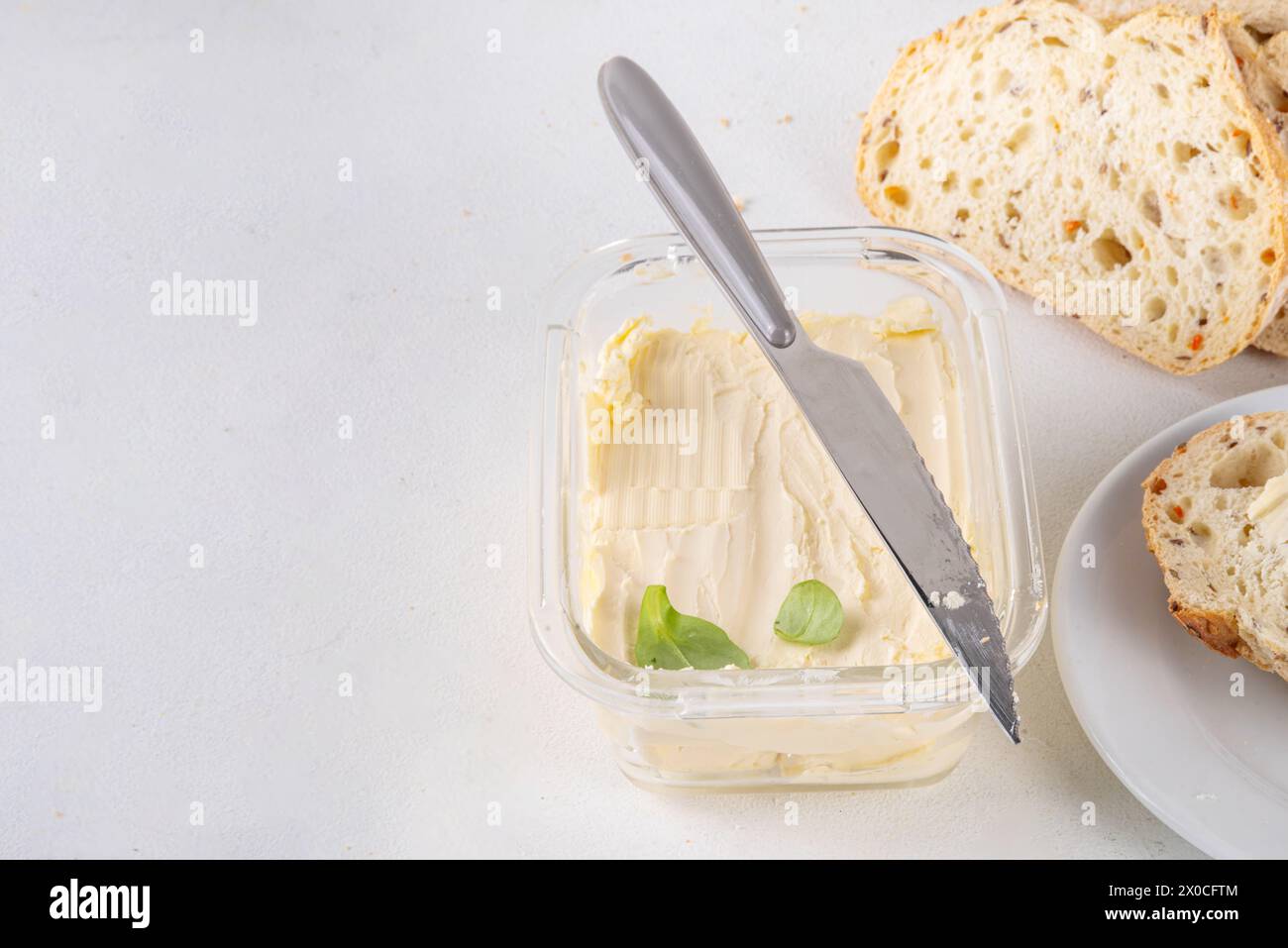 Homemade Vegan Butter, non-dairy creamy, plant based alternative butter with soy bean leave, and home baked bread on kitchen white table background Stock Photo