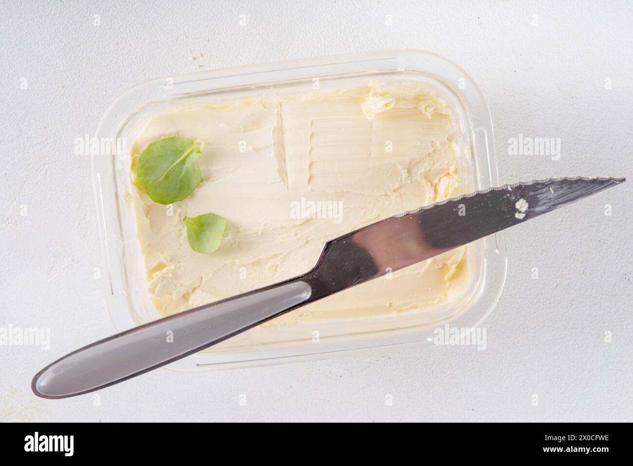 Homemade Vegan Butter, non-dairy creamy, plant based alternative butter with soy bean leave, and home baked bread on kitchen white table background Stock Photo