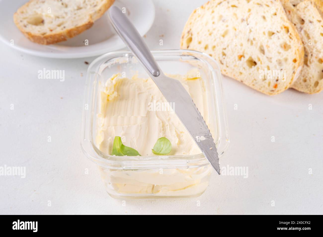 Homemade Vegan Butter, non-dairy creamy, plant based alternative butter with soy bean leave, and home baked bread on kitchen white table background Stock Photo