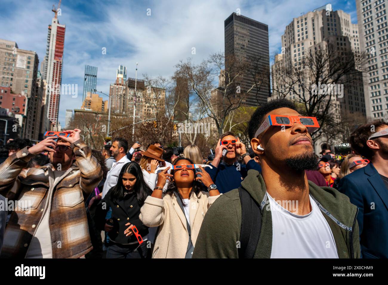 Hundreds of people gather in Flatiron Plaza in New York for a viewing party to watch, wearing their eye protection, the solar eclipse on Monday, April 8, 2024. New York City was not in the path of totality with the moon covering 89 percent of the sun during the 3:15 to 3:30PM window. (© Richard B. Levine) Stock Photo