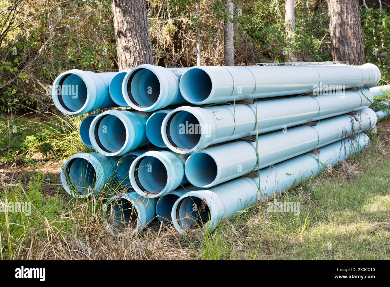 Pipes bundle for underground water mains construction, sewer pvc blue plastic industrial equipment by woodland area, Houston TX USA. Stock Photo