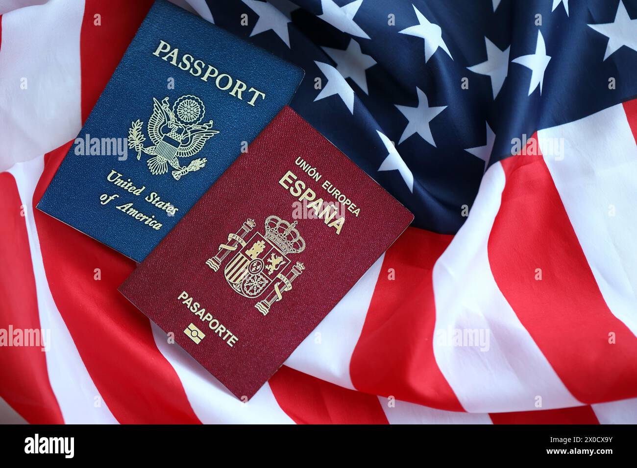 Passport of Spain with US Passport on United States of America folded flag close up Stock Photo