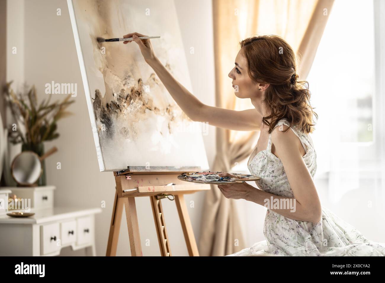 Beautiful female painter enjoying while painting in home art studio. Woman Artist Works on Abstract acrylic painting in the art studio. Stock Photo