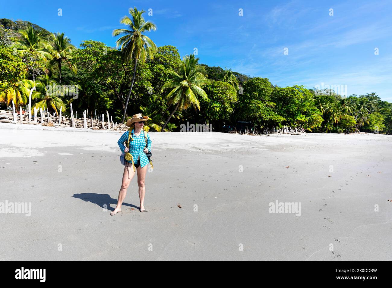 Woman with a straw hat, tourist, exploring on a beach Playa Montezuma near Montezuma village on a beautiful summer sunny day, Costa rica Stock Photo