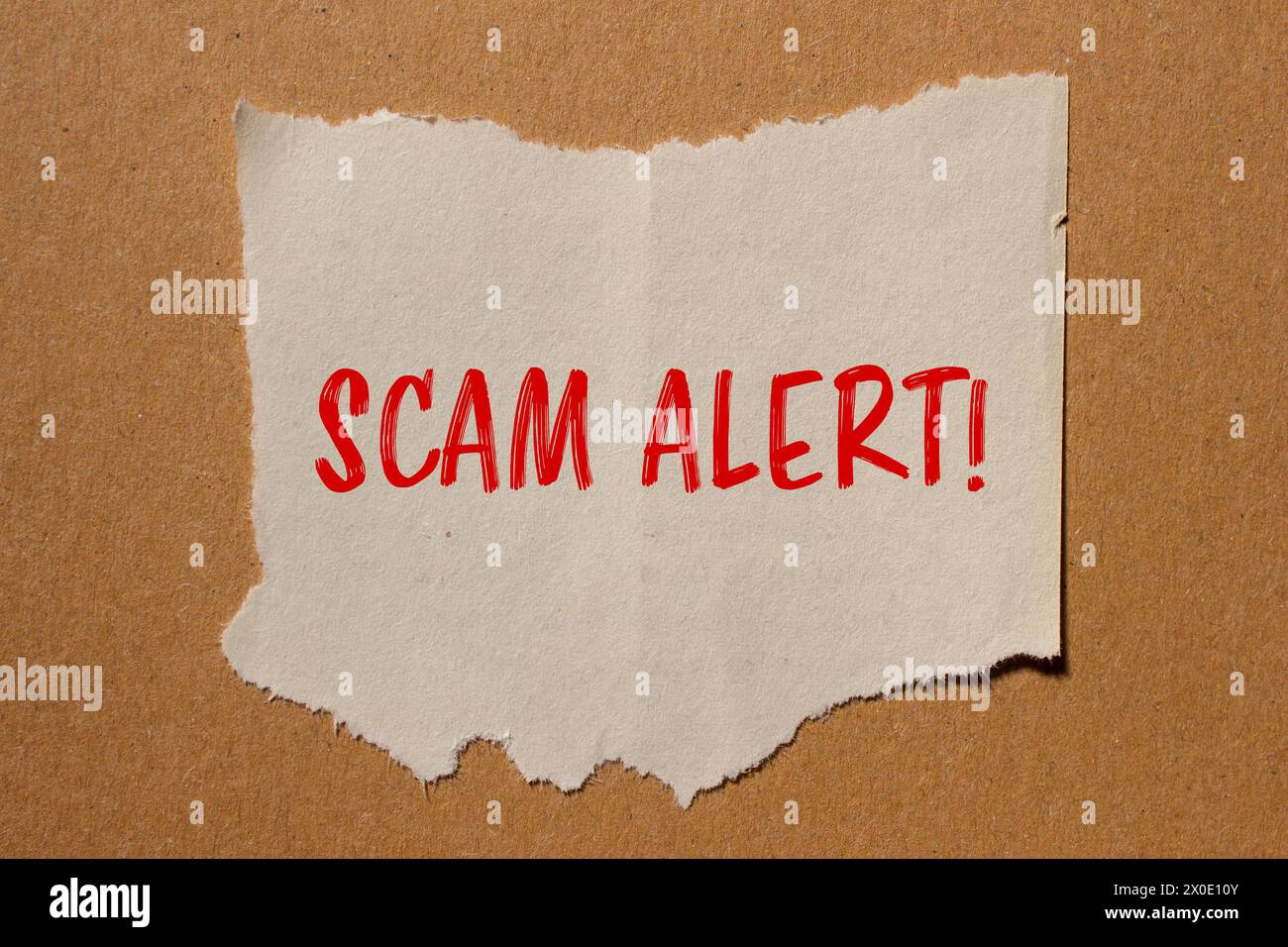 Scam alert words written on ripped paper with brown background. Conceptual symbol. Copy space. Stock Photo