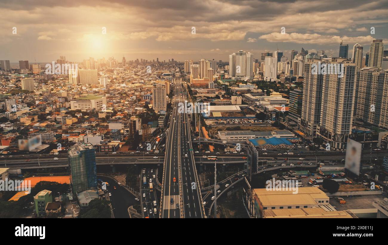 Cityscape at sun light with cross highway, streets, skyscrapers aerial. Bridge traffic road with driving cars at summer sunny day. Philippines capital cityscape of Manila town at drone shot Stock Photo