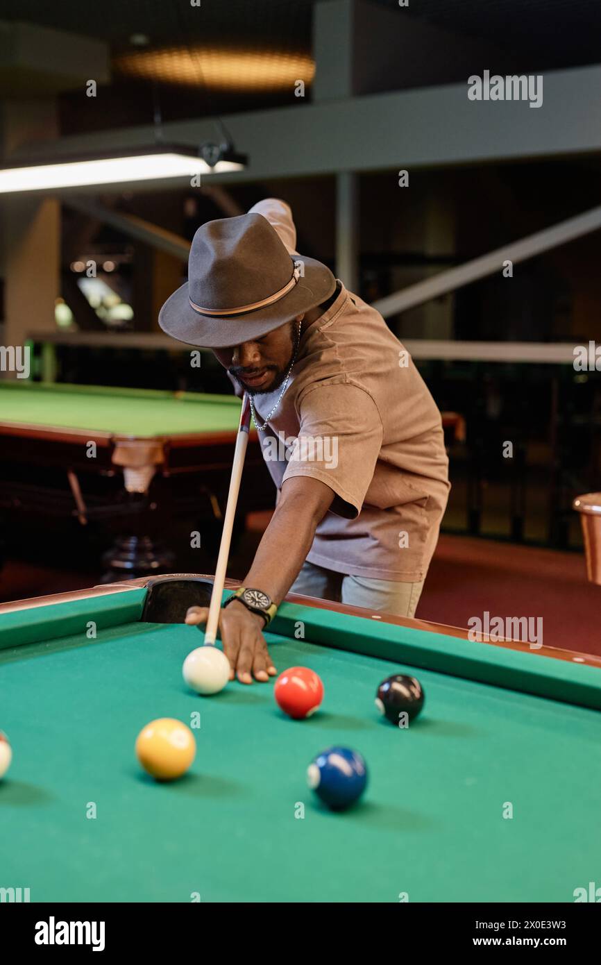 Vertical portrait of Black man wearing hand and playing pool at ...