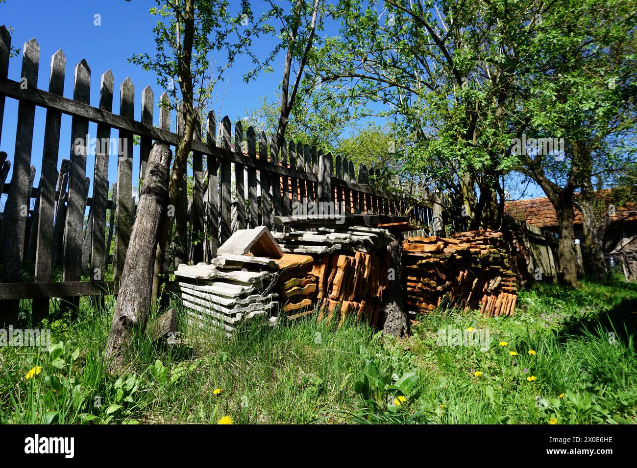 Weathered roofing tiles on old farm, peaceful stil life of fence in sunshine on green grass, traditional farm in Boljanic, Doboj, Republic of Srpska Stock Photo