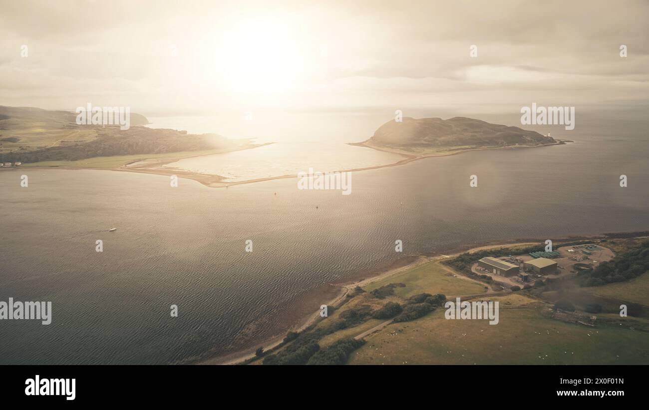 Sun flare at ocean bay reflection aerial. Majestic seascape at mountainous islands at Campbeltown, Scotland, Europe. Bright sunlight at sea coast with green mountain islets. Cinematic soft light shot Stock Photo