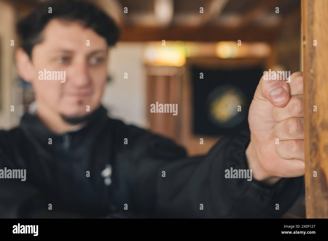 Selective focus on a man's fist training martial arts with a wooden dummy in the practice room. Stock Photo