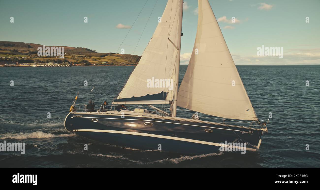 Yacht sailing on open sea at windy day aerial. Sun shine over white sail boat at ocean bay. Sailboat cruise at serene seascape. Amazing ship racing at summer sunny day. Cinematic drone shot Stock Photo