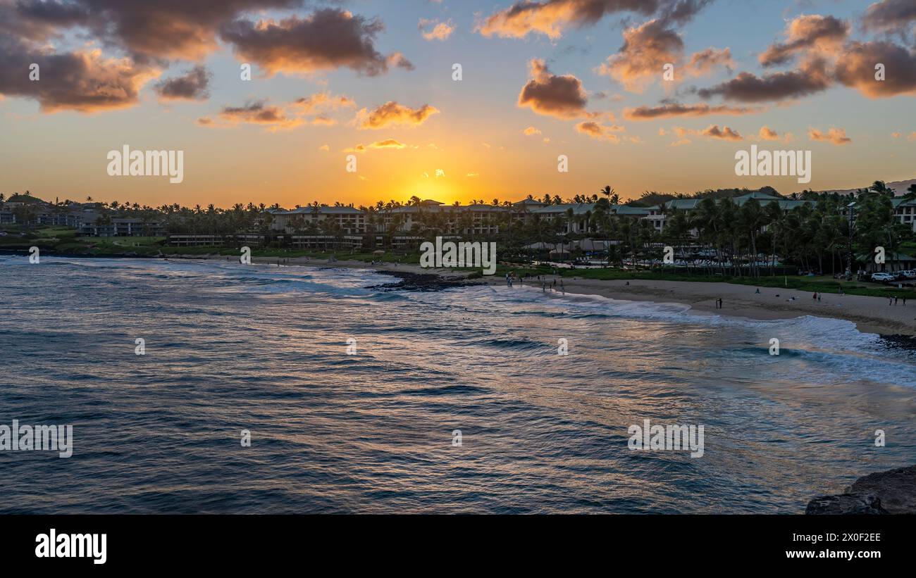 The sun sets over Shipwreck Beach and the Grand Hyatt Kauai Resort and Spa on the island of Kauai, Hawaii, USA. Stock Photo