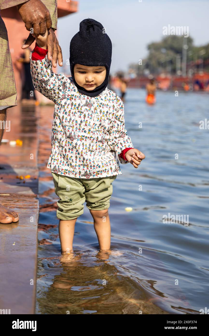 innocent toddler holing grand father finger and standing at holy river at morning from flat angle Stock Photo