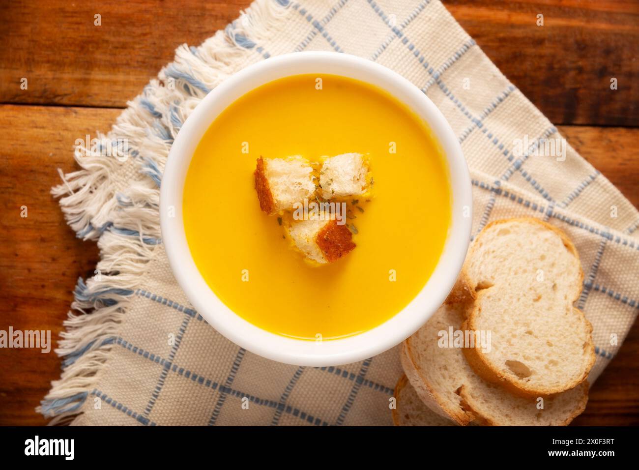 Homemade carrot and pumpkin cream soup. Easy, nutritious and healthy recipe. Served in a white bowl with bread croutons. Perfect to accompany everyday Stock Photo
