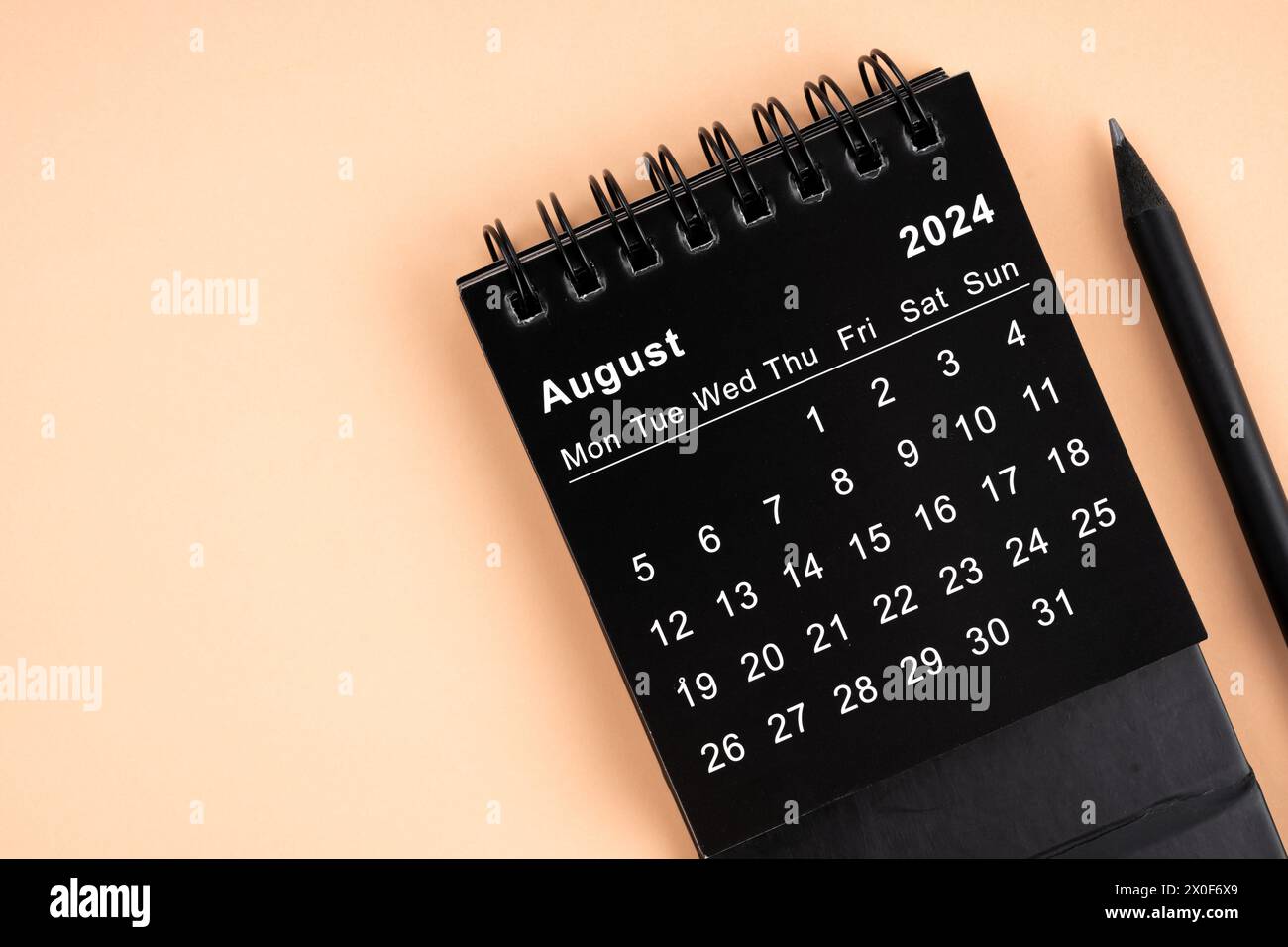 Augustl 2024 Black spiral desktop calendar and wooden pencil on yellow ...