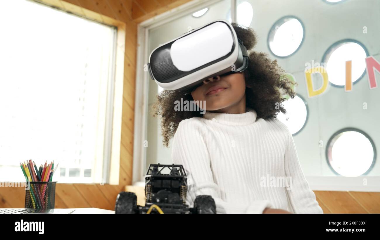 Smart african girl wearing VR vision glasses while hold car model. Student study visual reality and holding robotic model. Child using technology Stock Photo