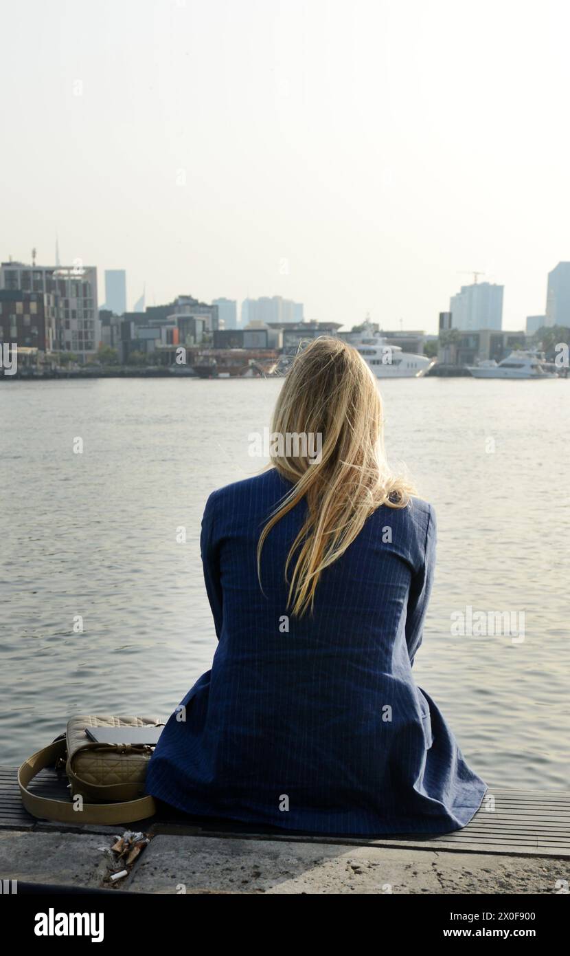 A woman enjoying the view of the Dubai Creek and Old Dubai. Deira, Dubai, UAE. Stock Photo
