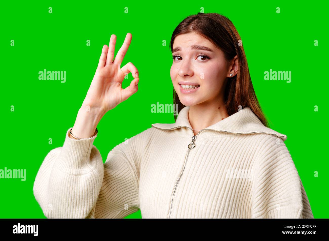 A woman dressed in a skirt and sweater is standing and waving her hand in the air, possibly in a greeting or to get someones attention. Stock Photo