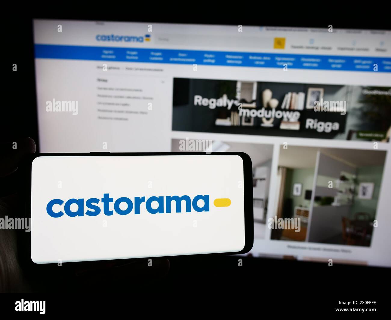 Person holding smartphone with logo of home improvement store chain company Castorama in front of website. Focus on phone display. Stock Photo