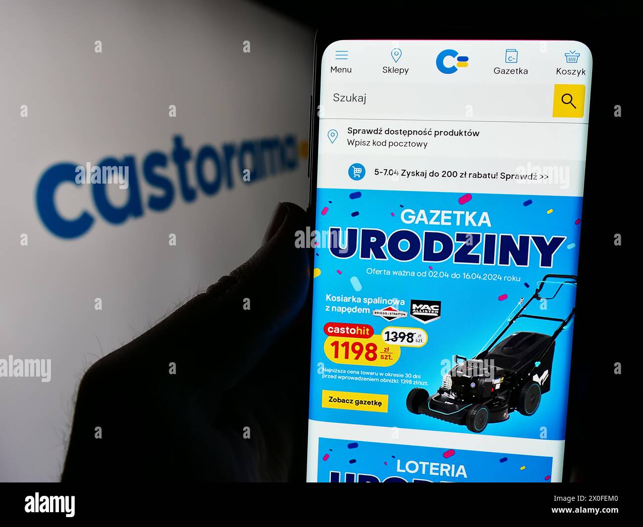 Person holding smartphone with webpage of home improvement store chain company Castorama in front of logo. Focus on center of phone display. Stock Photo
